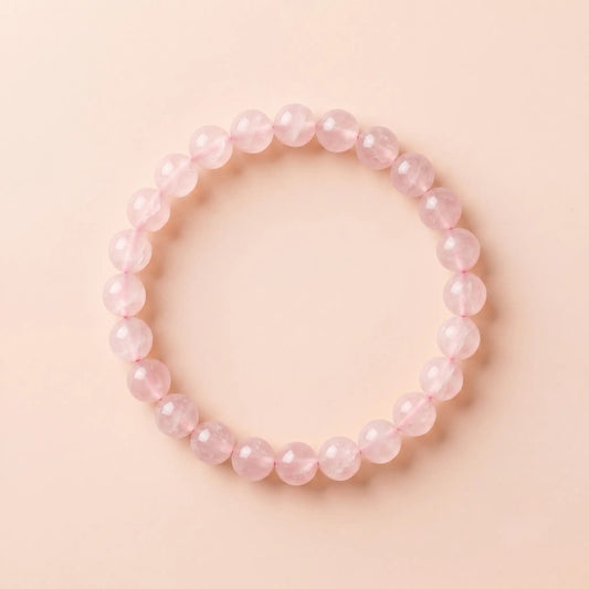 A premium natural rose quartz healing bracelet made of 8mm smooth round beads, elegantly arranged in a perfect circle on a soft blush pink matte surface under natural daylight